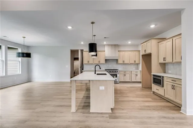 a large kitchen with stainless steel appliances granite countertop a stove top oven a sink and a refrigerator