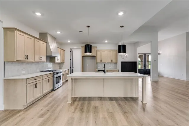 a kitchen with stainless steel appliances a sink a stove a refrigerator and cabinets