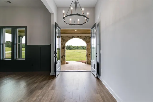 a view of a hallway with wooden floor and a chandelier