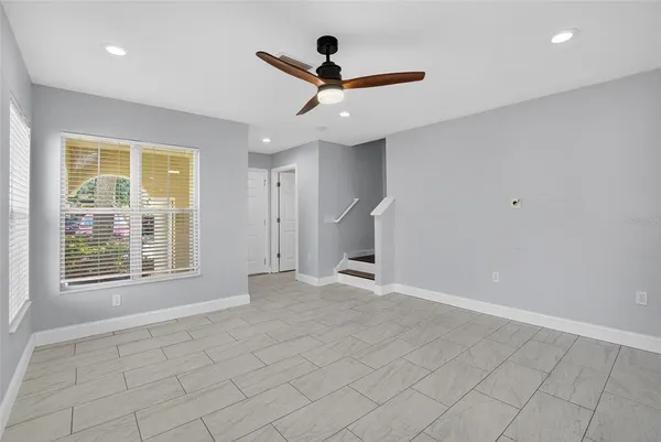 an empty room with ceiling fan and window