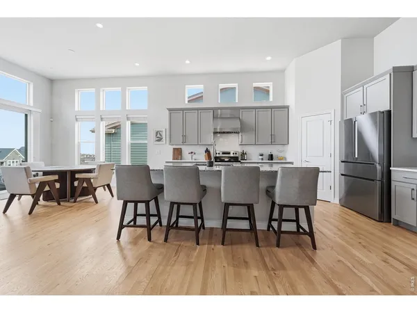 a open dining room with stainless steel appliances kitchen island granite countertop a dining table chairs and a refrigerator