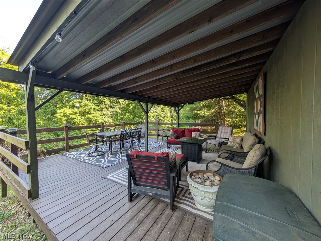 6700 McCaslin Road Nashport, OH 43830 - Photo 3 of 30 Expansive covered deck featuring wood-finish flooring, a metal roof, exposed wood beams, and perimeter railing