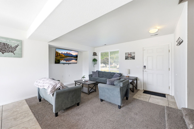 5485 Heather Way Tooele, UT 84074 - Photo 14 of 41 Living area featuring a mix of carpet and tile flooring, a multi-pane window with horizontal blinds, and a white six-panel entry door