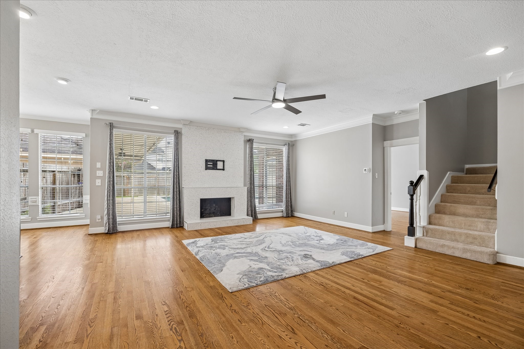 7915 Huddersfield Court Spring, TX 77379 - Photo 13 of 37 Spacious family room with hardwood floors, fireplace, updated ceiling fan, recessed lighting, and large windows overlooking the backyard and pool area.