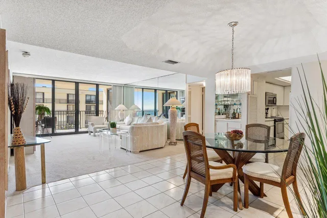 a view of a dining room and livingroom with furniture wooden floor a chandelier