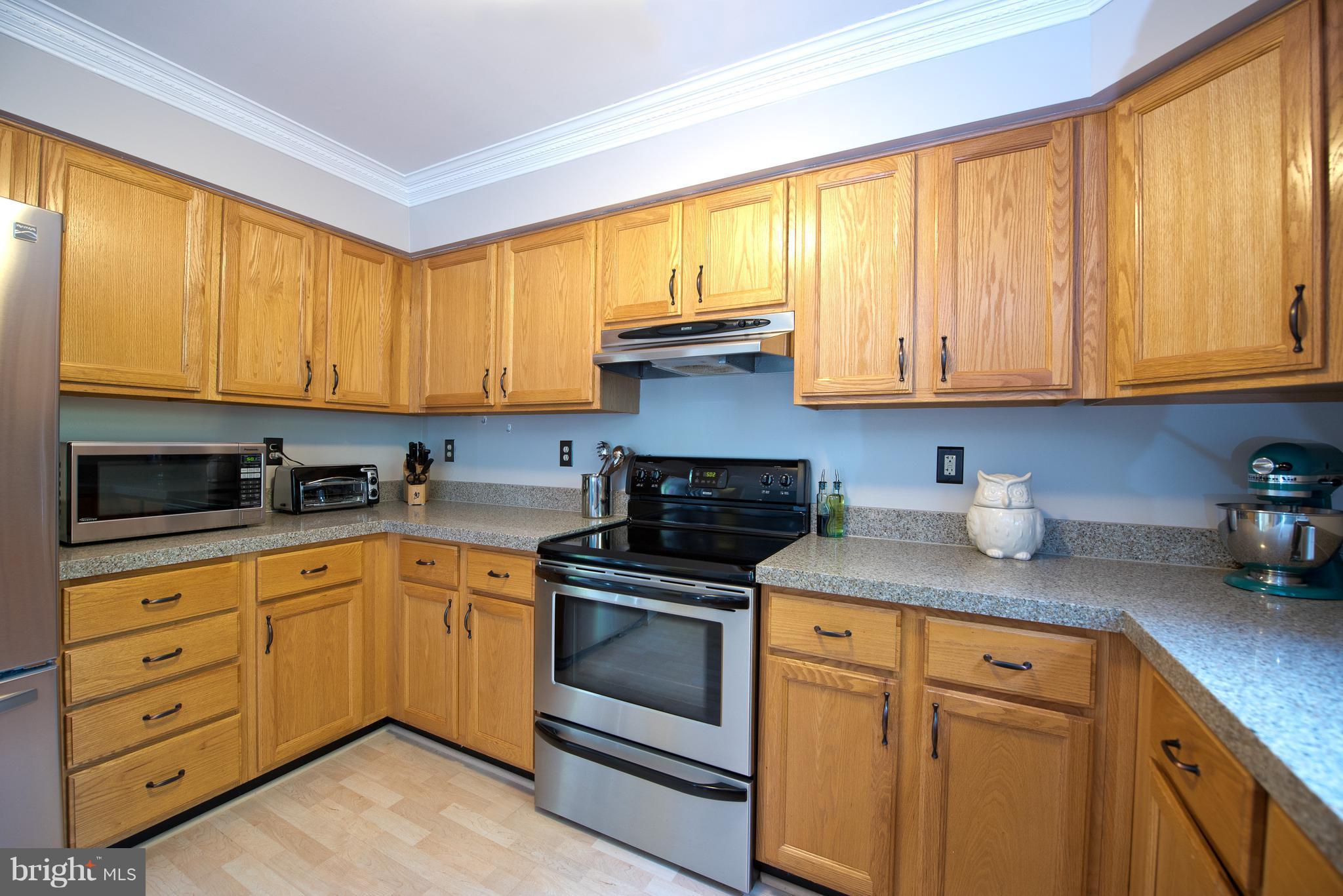 6163 Good Hunters Ride Columbia, MD 21045 - Photo 11 of 30 a kitchen with granite countertop wooden cabinets stainless steel appliances and a window