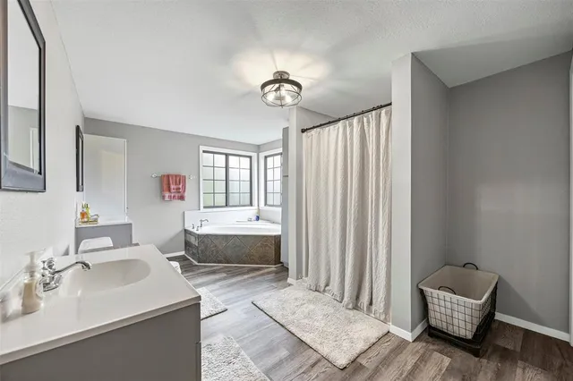 a spacious bathroom with a tub sink and mirror