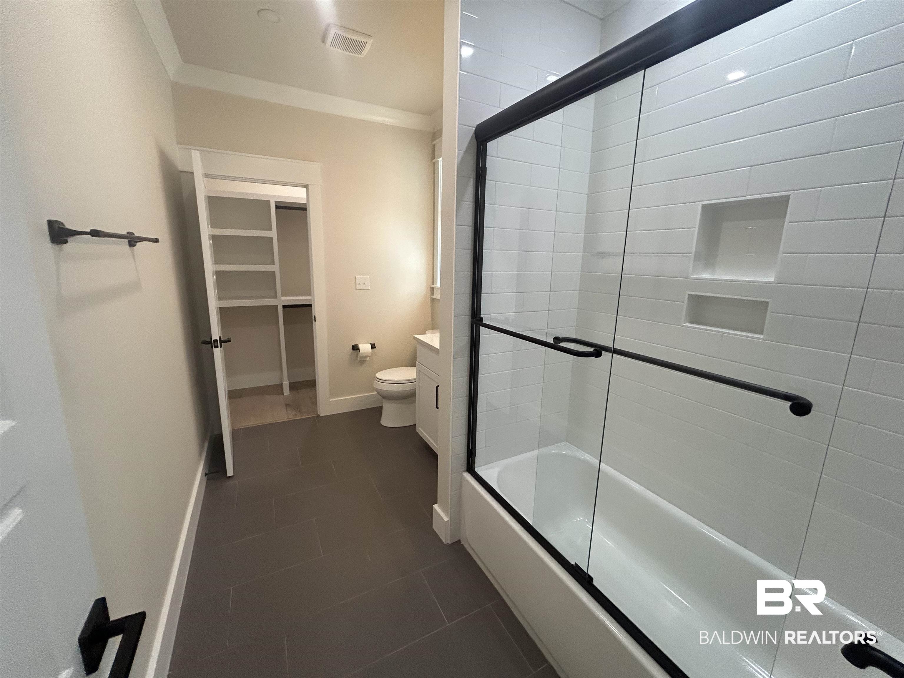 5122 Pine Road Orange Beach, AL 36561 - Photo 15 of 24 Bathroom featuring ornamental molding, a spacious closet, combined bath / shower with glass door, and dark tile patterned floors