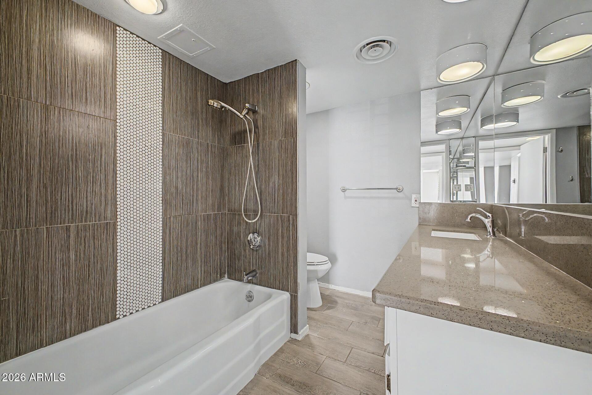 207 West Clarendon Avenue, Unit B2 Phoenix, AZ 85013 - Photo 11 of 30 a bathroom with a granite countertop bathtub shower sink and mirror