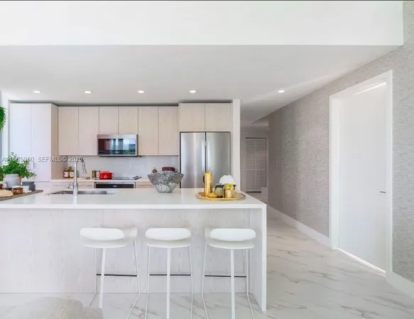 a kitchen with stainless steel appliances granite countertop a sink a stove a refrigerator and white cabinets with wooden floor
