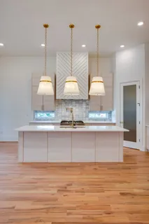 a large kitchen with granite countertop a large counter top a refrigerator and stainless steel appliances