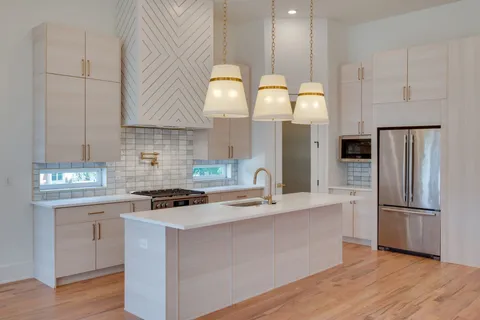 a view of an empty room with wooden floor and chandelier
