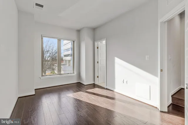 an empty room with wooden floor and windows