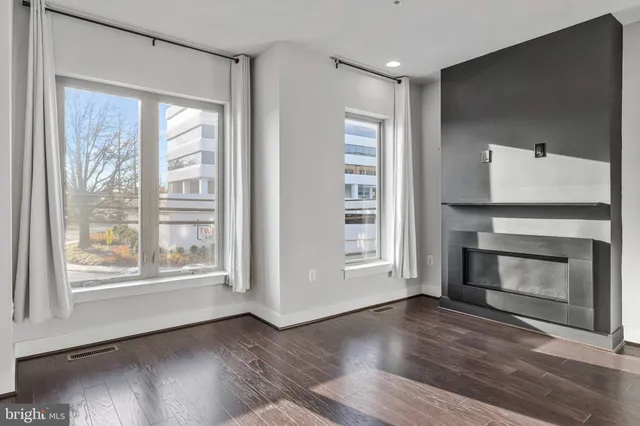 a view of an empty room with wooden floor fireplace and a window