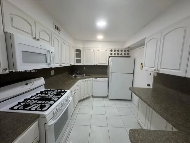 a kitchen with white cabinets and appliances