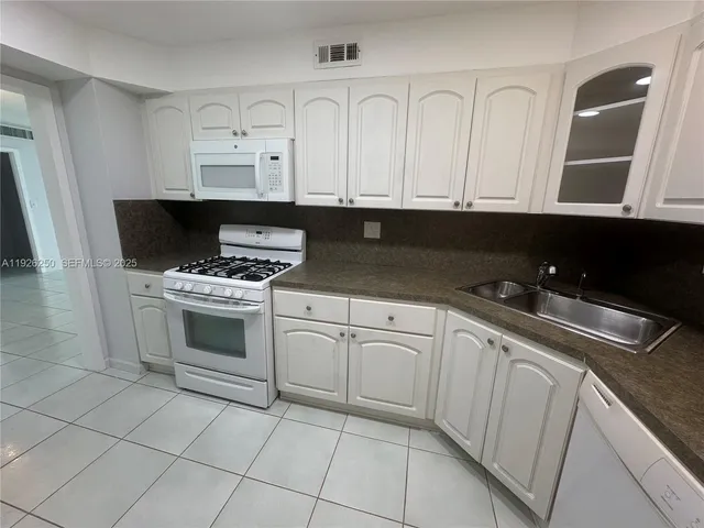 a kitchen with white cabinets and appliances