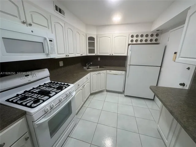 a kitchen with a refrigerator a stove a sink and cabinets