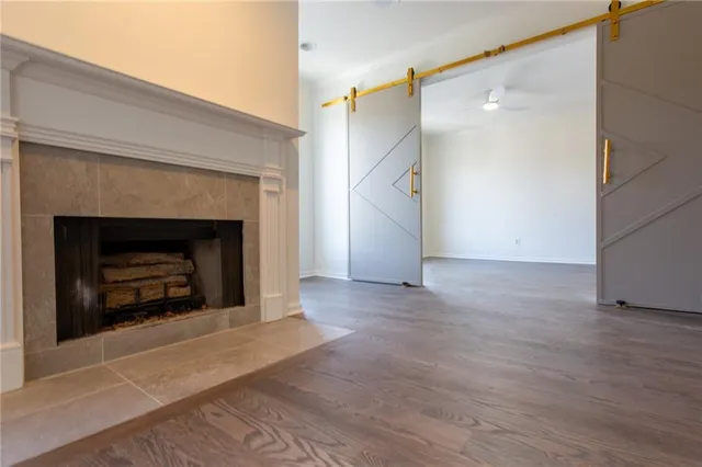 a view of an empty room with wooden floor fireplace and a window