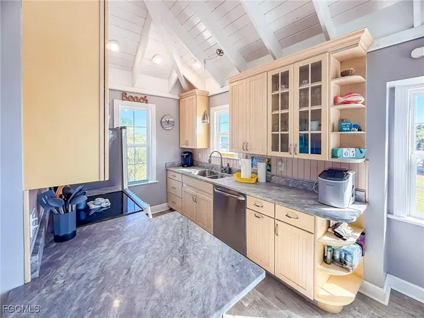 a large kitchen with stainless steel appliances granite countertop a sink dishwasher a stove a dining table and chairs next to a window