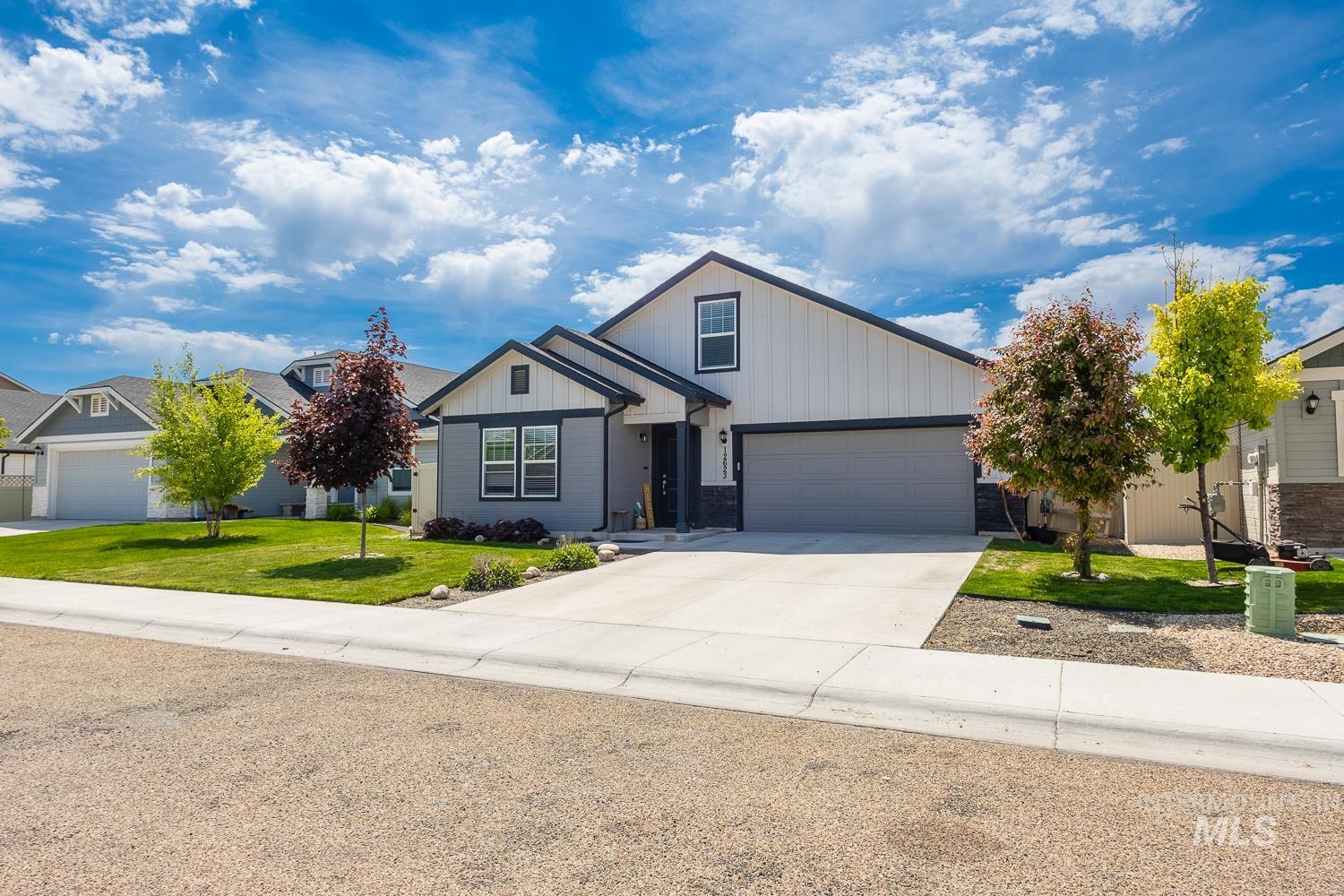 12623 Shadow Peak Street Caldwell, ID 83607 - Photo 4 of 50 Contemporary home with a two-tone exterior, featuring a gray garage door, white vertical siding, and dark trim