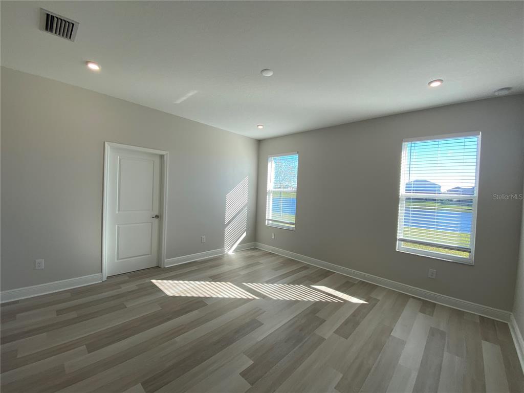 34273 Radley Way Wesley Chapel, FL 33545 - Photo 21 of 38 an empty room with wooden floor and windows