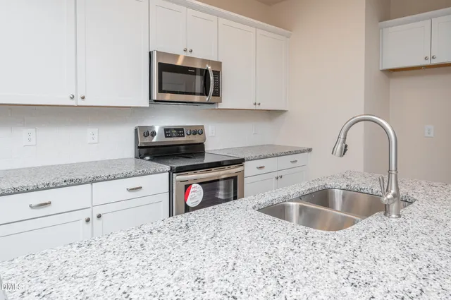 a kitchen with granite countertop a sink a microwave and cabinets