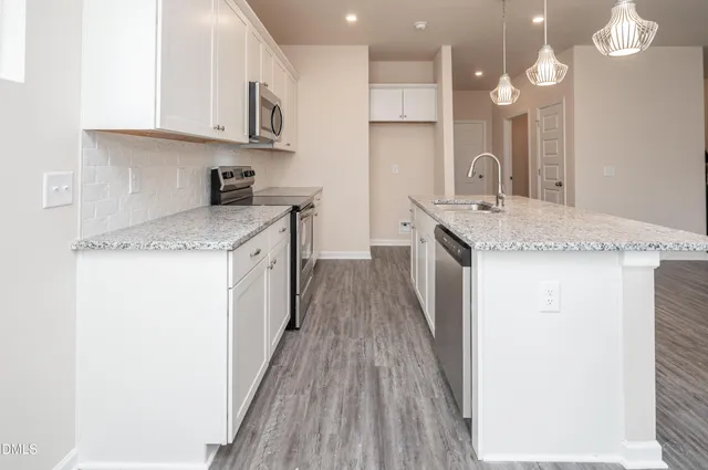 a kitchen with granite countertop a sink a counter top space stainless steel appliances and cabinets