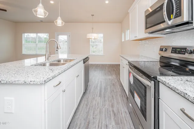 a kitchen with granite countertop stainless steel appliances a sink stove top oven and cabinets