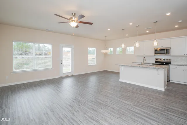 an open kitchen with kitchen island white cabinets and wooden floor