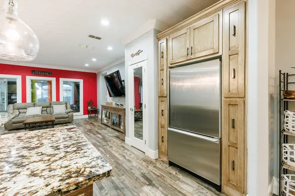 a kitchen with stainless steel appliances kitchen island granite countertop a refrigerator a stove and a wooden cabinets with wooden floor