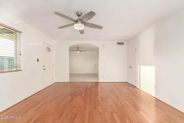 a view of empty room with wooden floor and ceiling fan