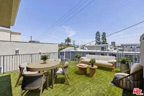 a view of a patio with couches chairs potted plants and wooden floor