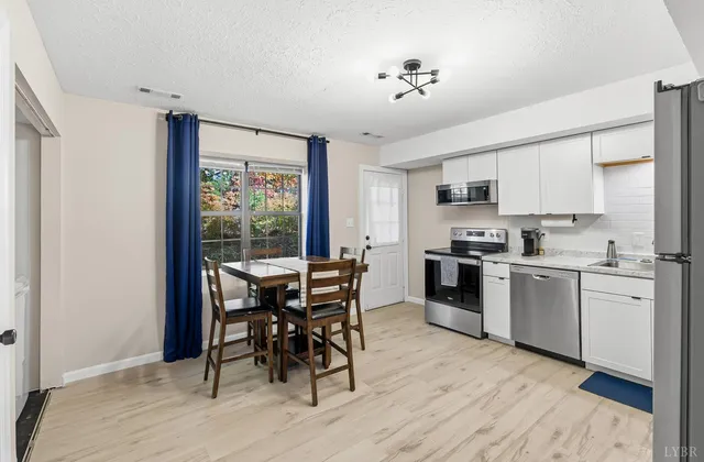 a kitchen with white cabinets and wooden floor