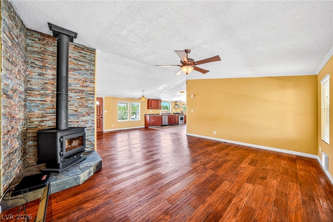 1831 West Horn Road Pahrump, NV 89048 - Photo 8 of 59 A spacious common area boasts warm wood flooring, a striking stone fireplace, and views into a contemporary kitchen.