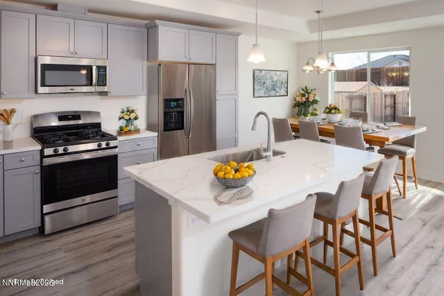 a kitchen with stainless steel appliances a stove a sink a microwave a refrigerator and white cabinets