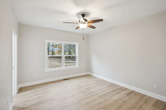an empty room with wooden floor and ceiling fan