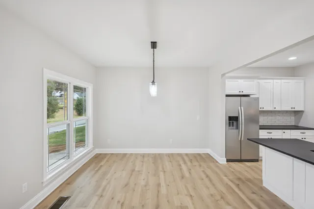 a view of an empty room with a window and wooden floor