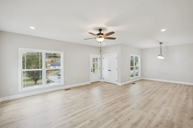a view of an empty room with a window and wooden floor