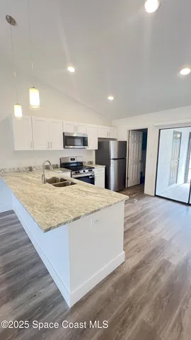 a large kitchen with kitchen island a stove a sink a refrigerator and white cabinets