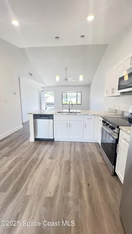a large kitchen with stainless steel appliances granite countertop a lot of cabinets and wooden floor