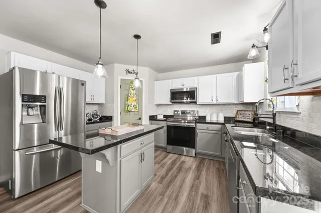 a kitchen with stainless steel appliances granite countertop a stove a refrigerator a sink dishwasher a oven with a dining table and chairs