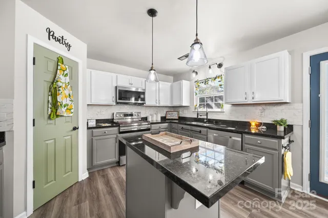 a kitchen with a sink dishwasher a stove and white cabinets with wooden floor