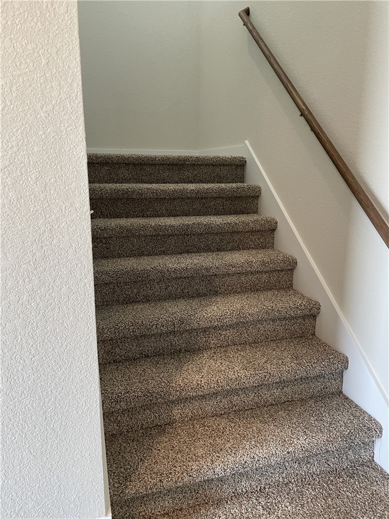609 Paddock Lane Georgetown, TX 78626 - Photo 15 of 40 Plush carpeted stairs ascend alongside a sturdy wooden handrail anchored to textured walls.