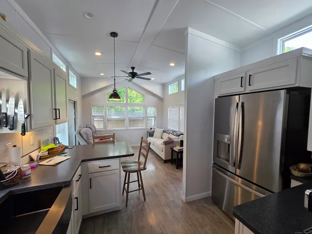 a living room with stainless steel appliances furniture a refrigerator a sink and a large window