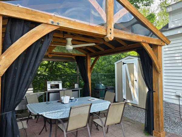 a view of patio with table and chairs under an umbrella with a small yard
