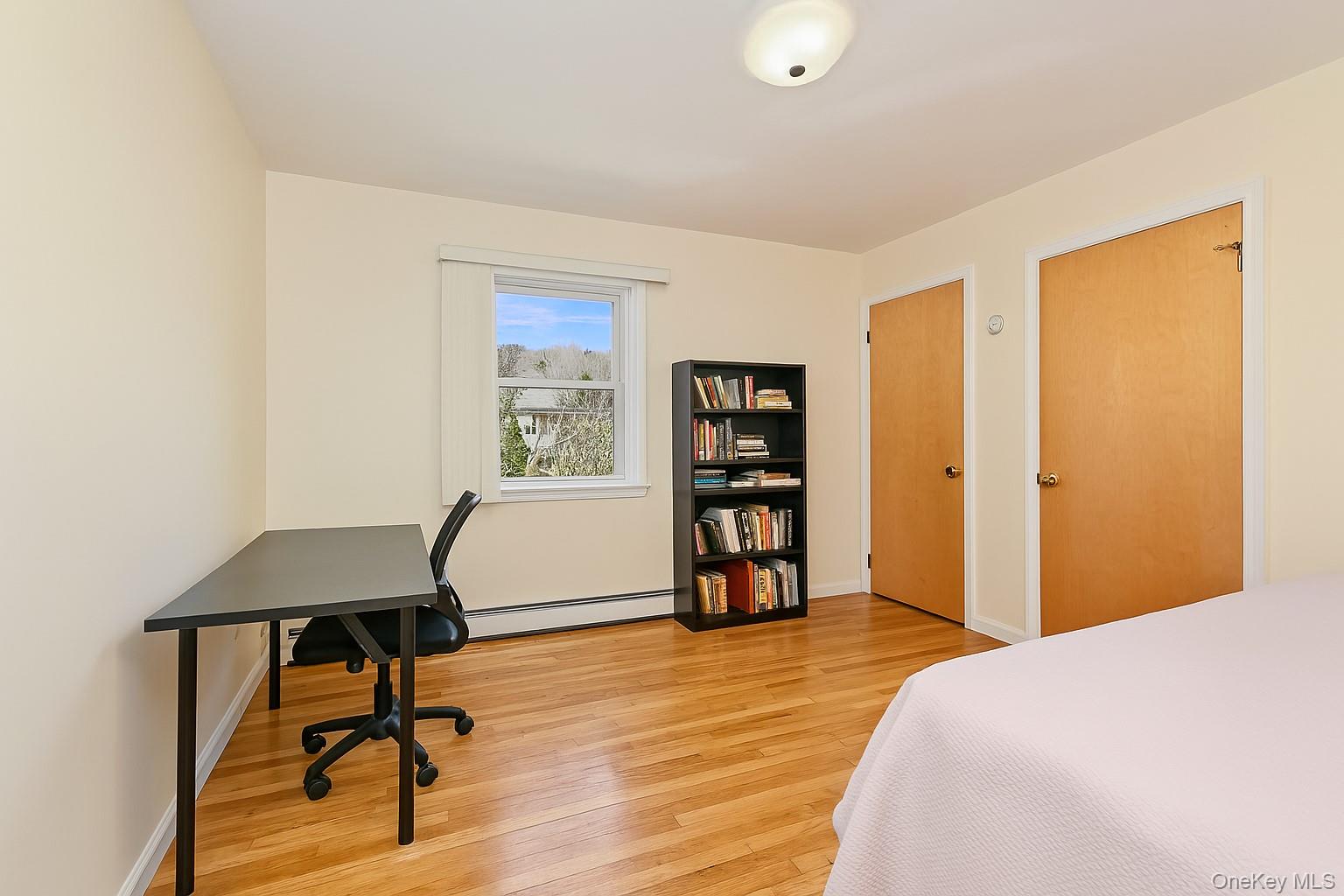568 Manville Road, Unit UPPER R Pleasantville, NY 10570 - Photo 25 of 32 Hardwood-style flooring throughout this room, featuring a window with natural light, two wood-paneled doors, and a ceiling-mounted light fixture
