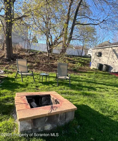 a view of a white house with a yard table and chairs