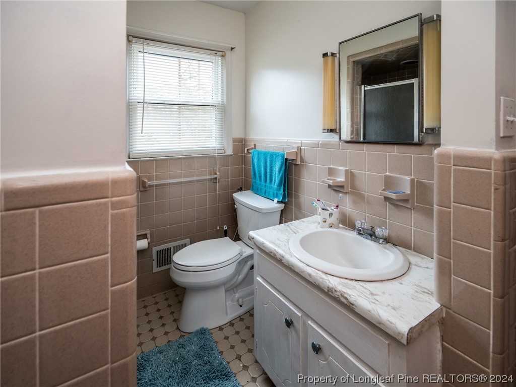 1982 Rowan Road, Unit R Lumberton, NC 28358 - Photo 32 of 43 a bathroom with a granite countertop toilet a sink and mirror