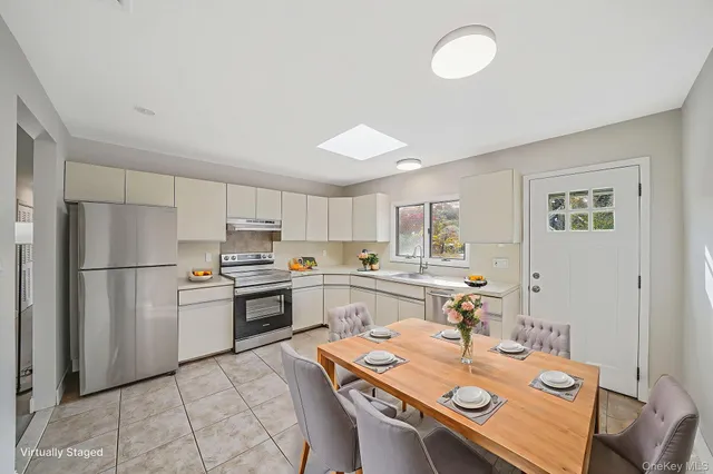 a kitchen with a refrigerator a stove a sink and a dining table with white walls