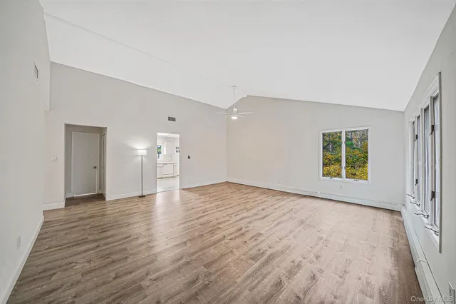 a view of empty room with wooden floor and window